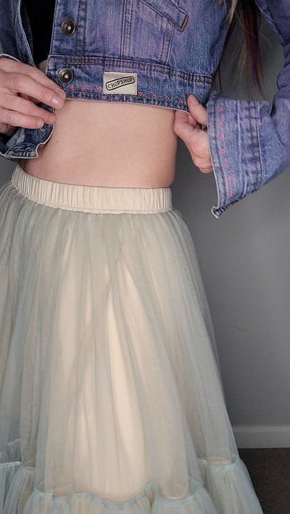 a woman wearing a denim jacket and a tulle skirt.