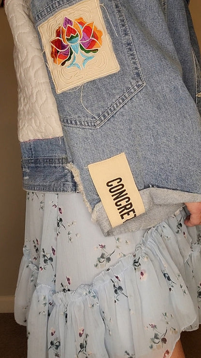 a woman wearing a denim jacket with a patch on it.
