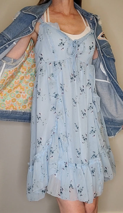 a woman wearing a blue dress and denim jacket.