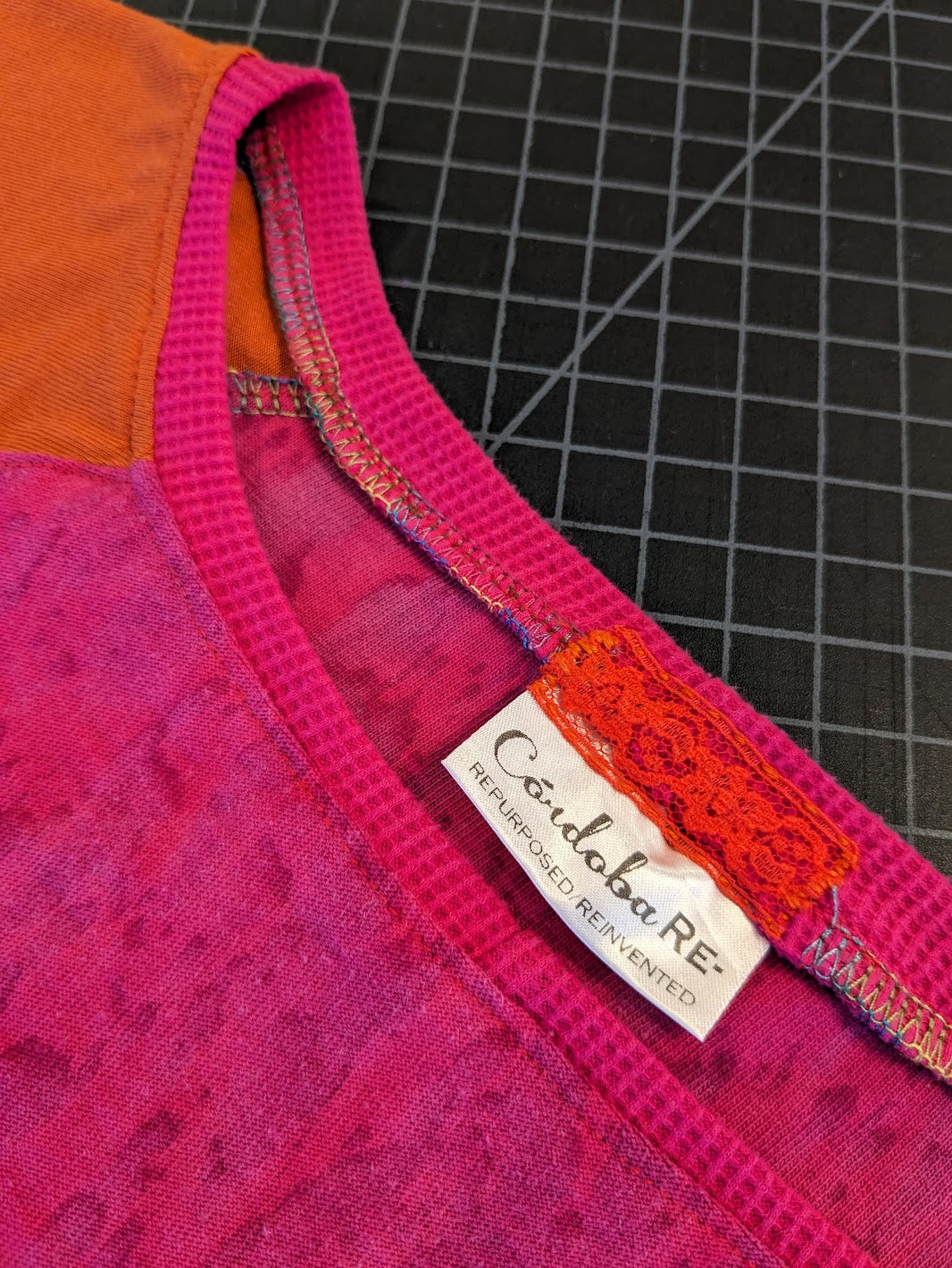 A close up of a pink and orange shirt with a label on it.