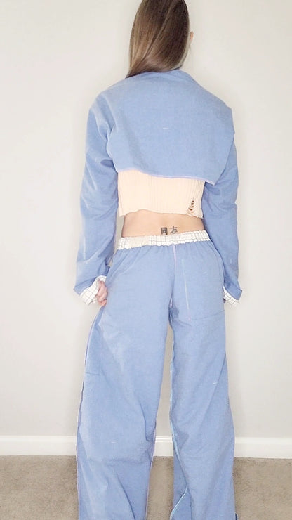 A woman is standing in a room wearing a blue jumpsuit.