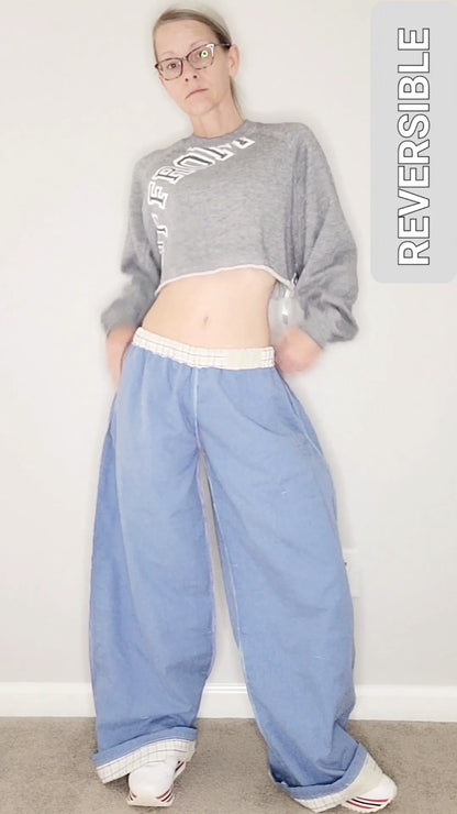 A woman is posing for a photo in a pair of blue wide leg pants.