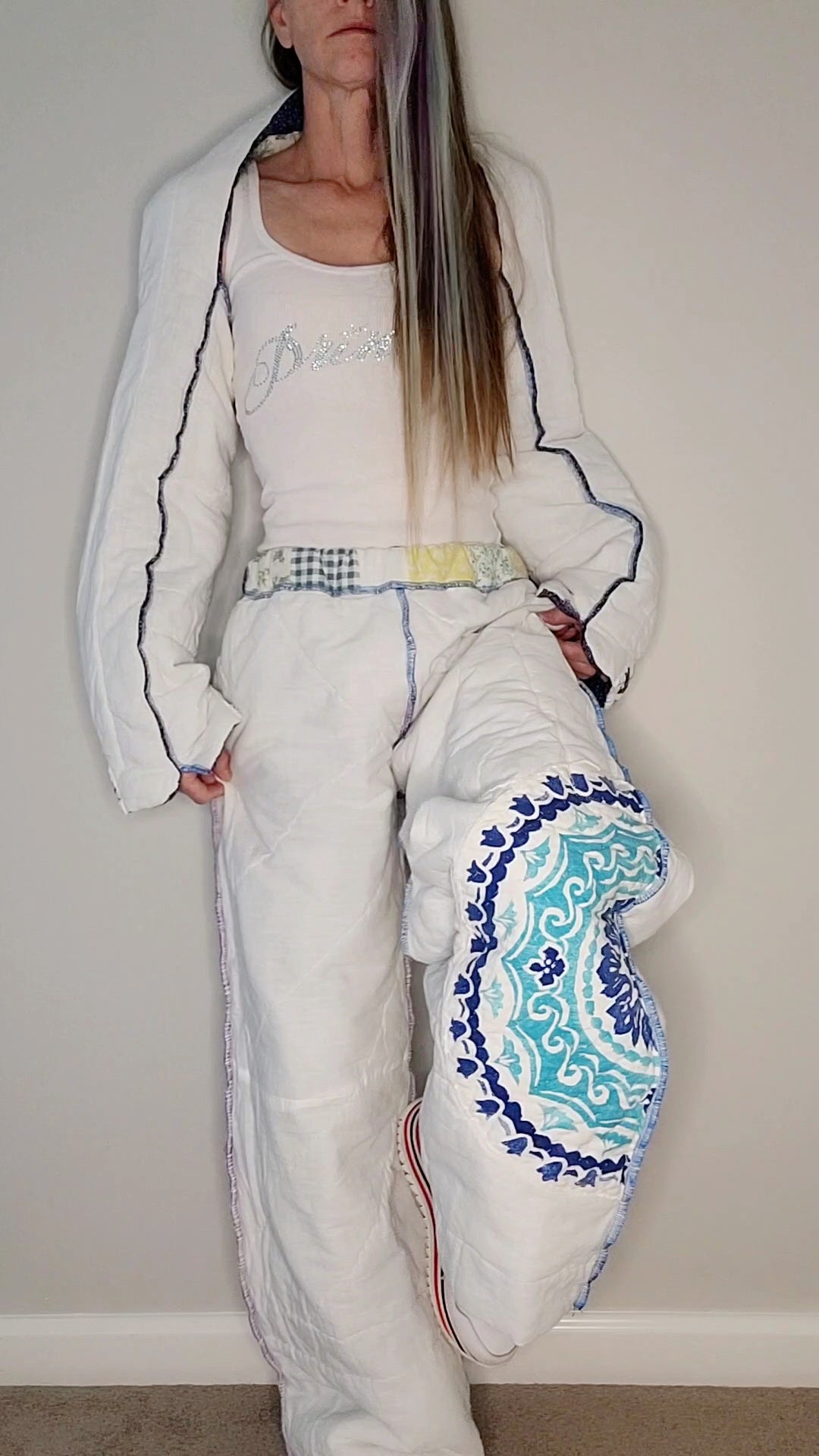 A woman in a white outfit posing in front of a wall.
