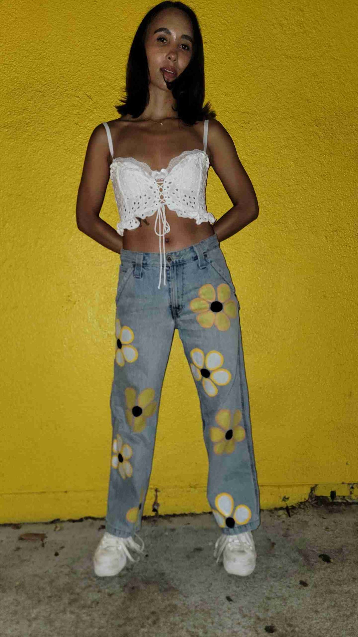 a woman standing in front of a yellow wall.