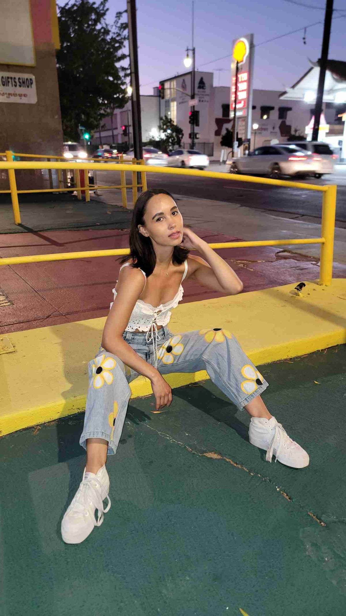 a woman sitting on the curb of a city street.