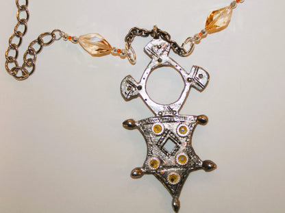 A necklace with a Aztec symbol pendant on it.