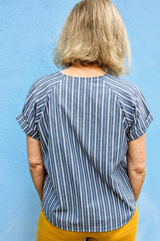 The back of a woman wearing a blue striped top and yellow pants.