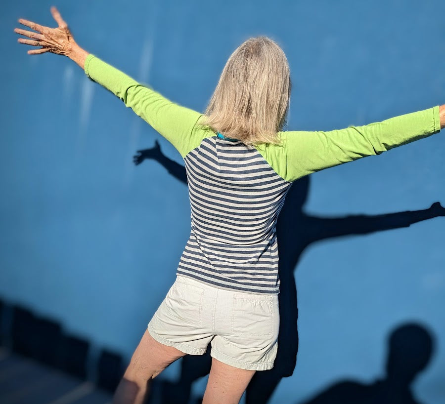 A woman with her arms outstretched in front of a blue wall.