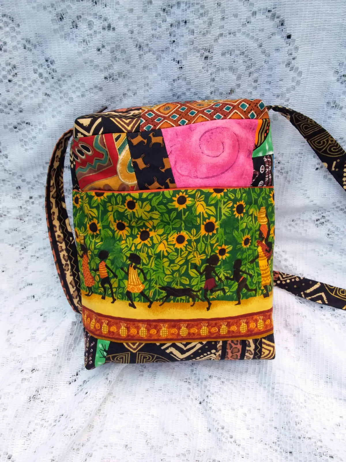 This lovingly handcrafted handbag evokes the feel of an African Village as women and children dance their way through a field of sunflowers and around the circumference of the bag.