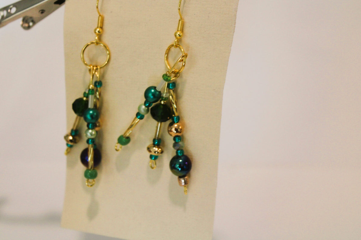 A pair of earrings with green and blue beads.