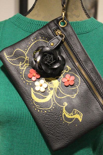 Green textured purse with floral design and a black charm hanging from the zipper.