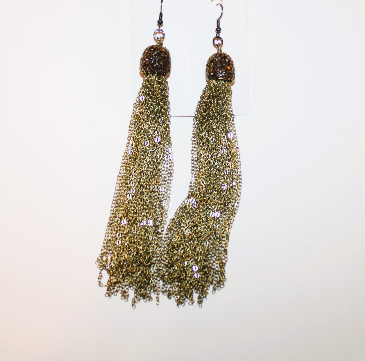 A pair of gold tassel earrings hanging on a wall.