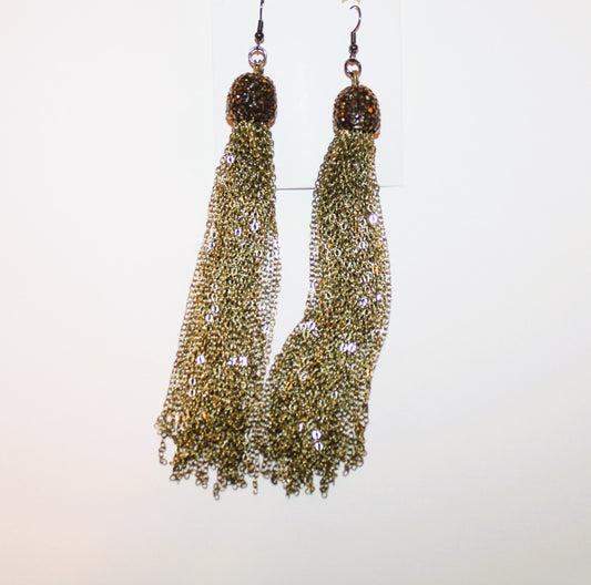 A pair of gold tassel earrings hanging on a wall.