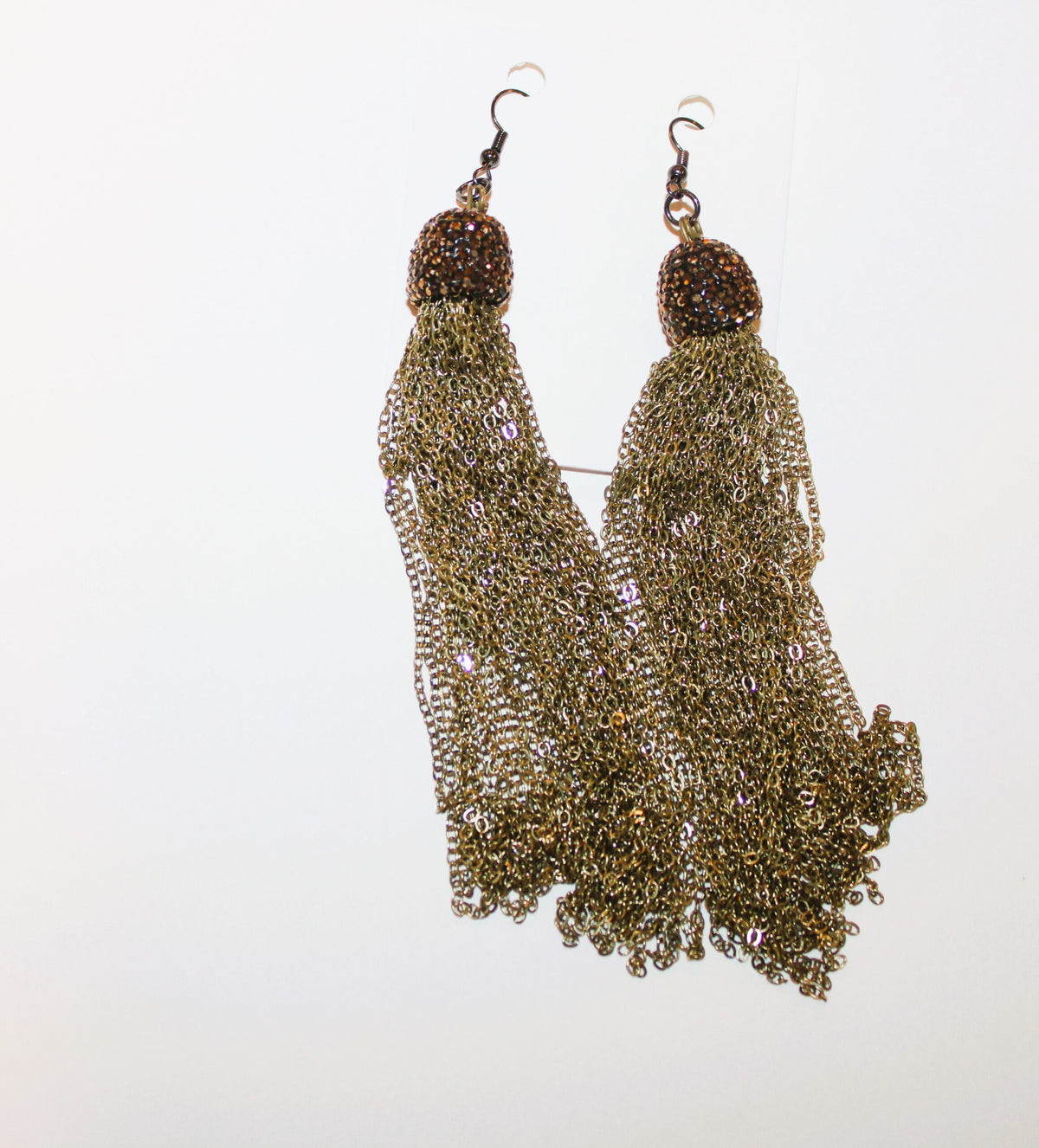 A pair of gold tassel earrings hanging on a white surface.