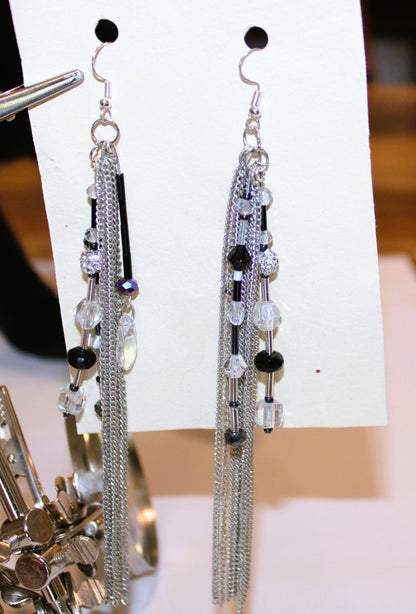 A pair of silver tassel earrings on a piece of paper.