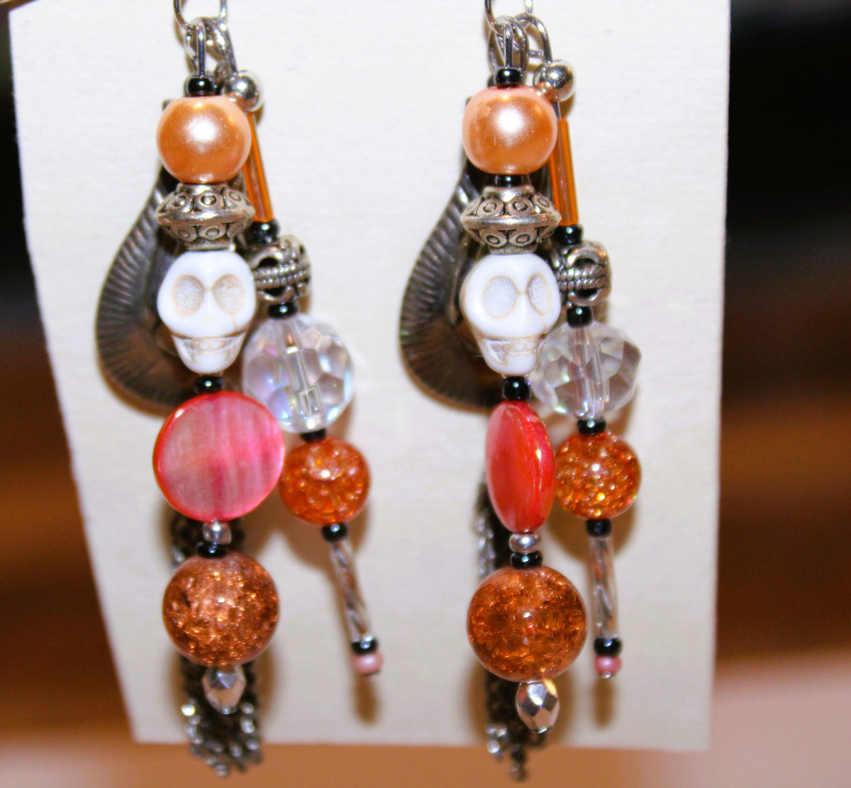 A pair of earrings with orange beads and tassels.
