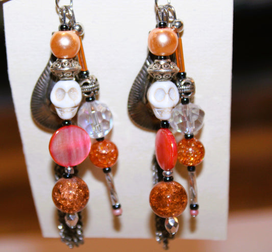 A pair of earrings with orange beads and tassels.