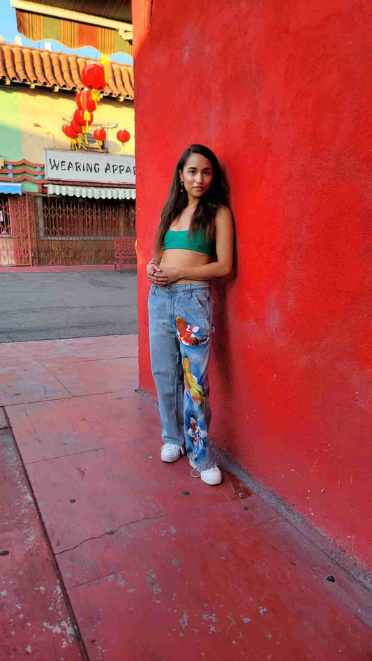 a young woman leaning against a red wall.
