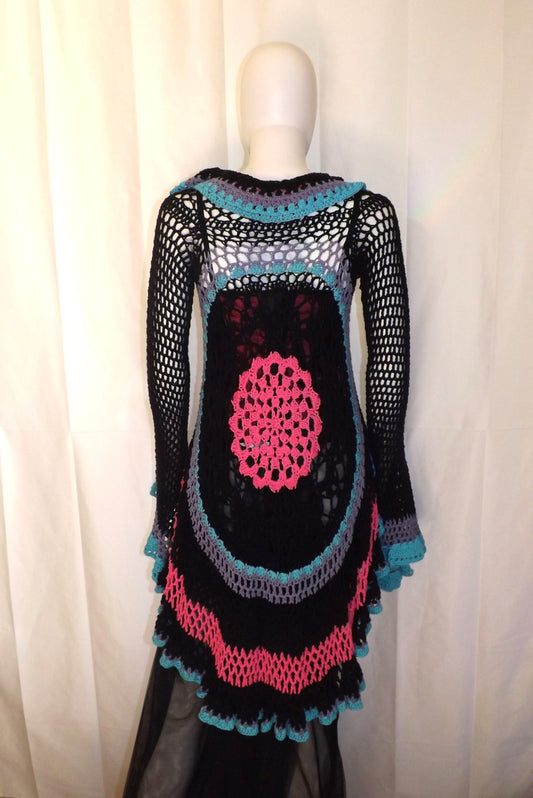 A black and pink crocheted dress on a mannequin.