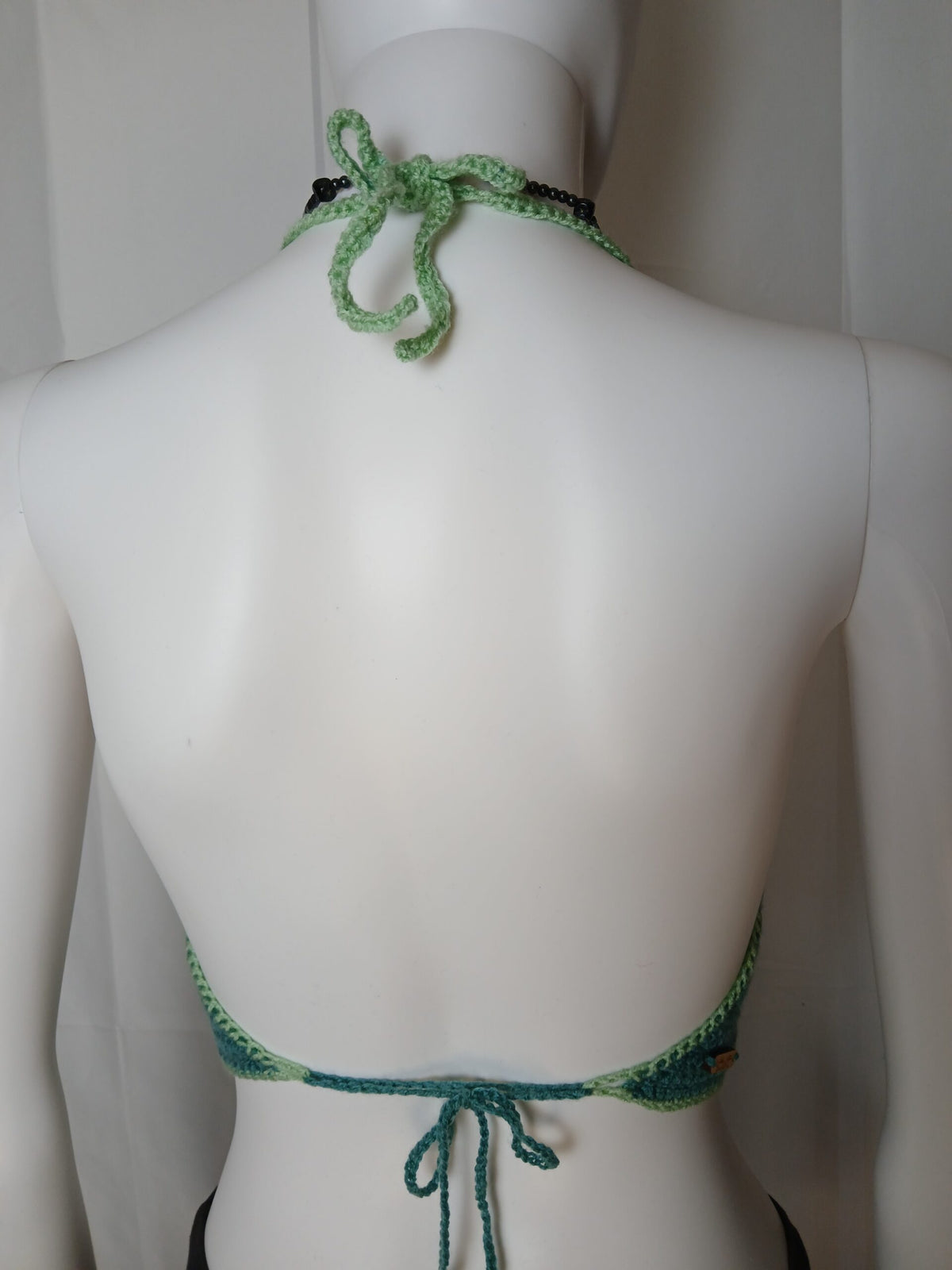 The back of a mannequin wearing a green halter.