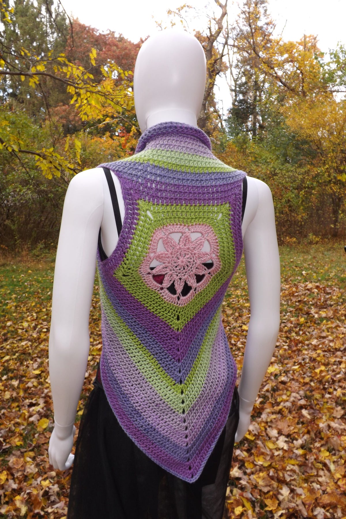 A crochet crop top vest with lotus flower design in shades of green, purple and pink.