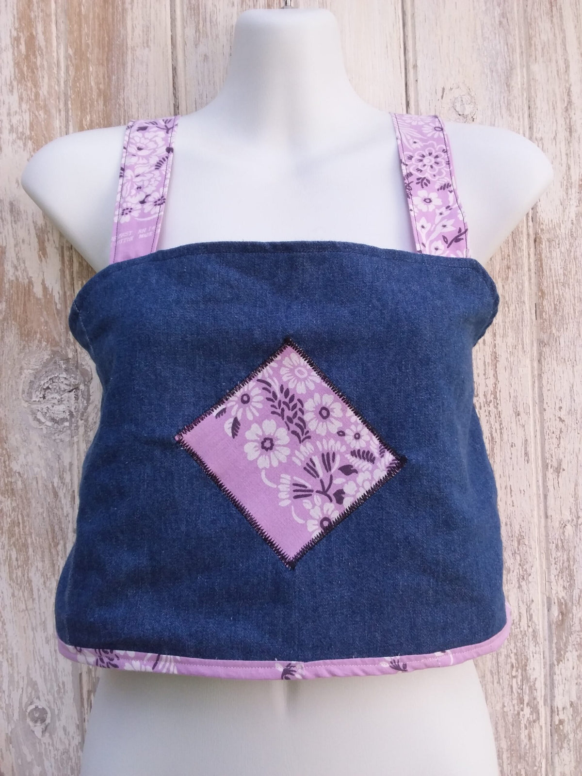 A mannequin wearing an upcycled denim crop top with purple bandana straps
