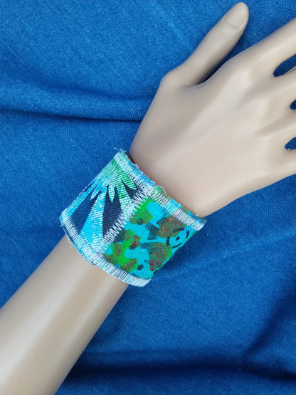 A hand painted recycled denim cuff bracelet in blue and green