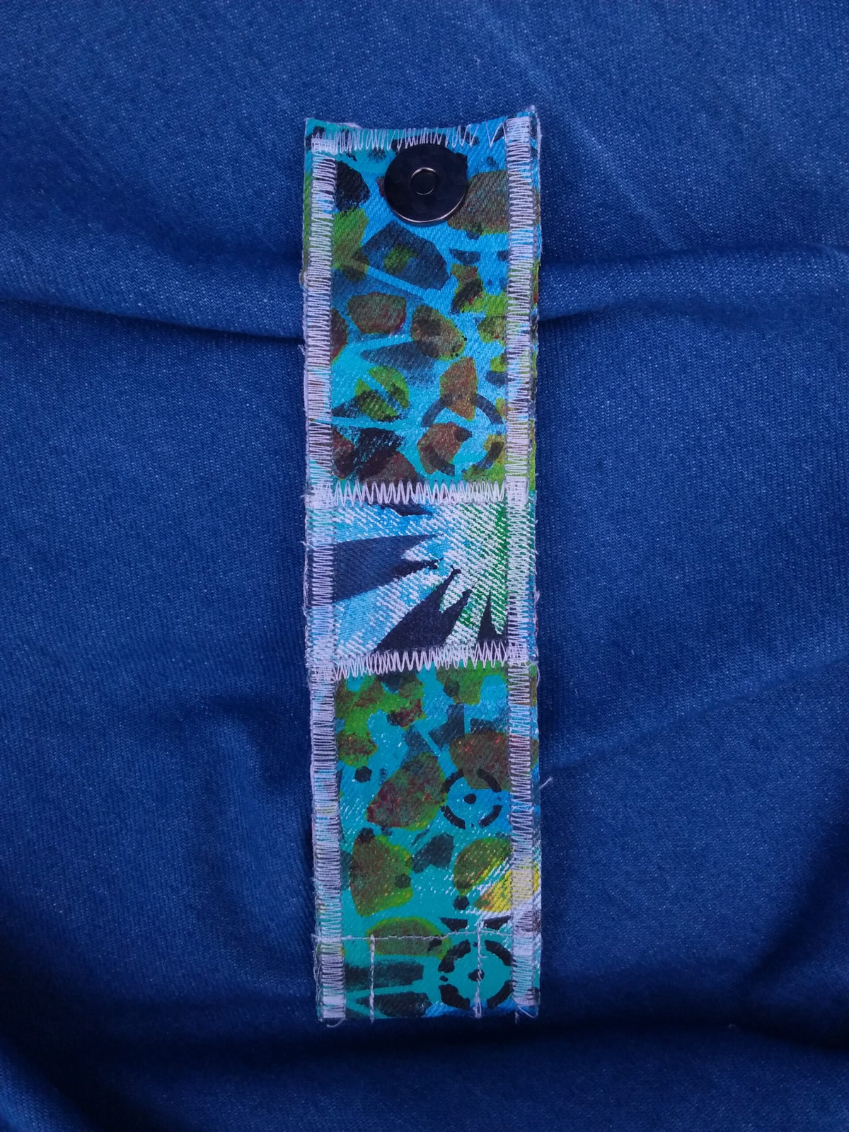A hand painted recycled denim cuff bracelet