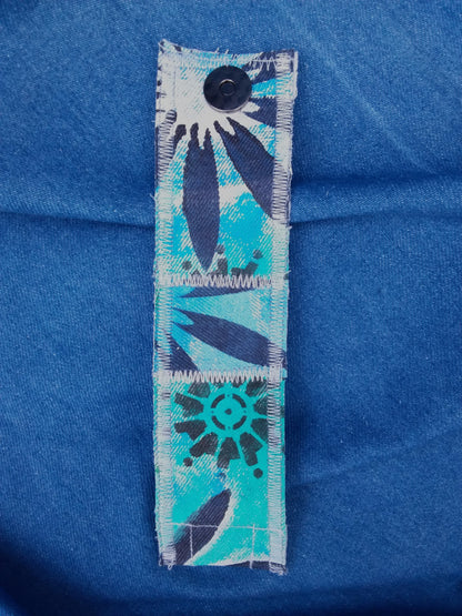 A hand painted, recycled denim cuff bracelet with a flower on it.