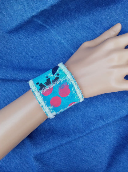 A upcycled denim cuff bracelet with blue gears and red polka dots.