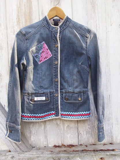 A denim jacket hanging on a wooden wall.