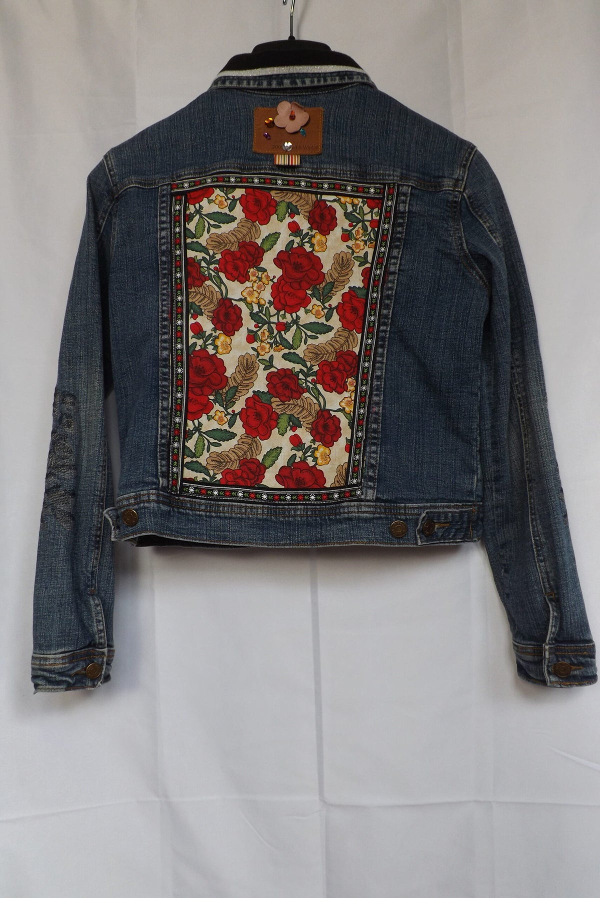 Red roses fabric and floral trim decorate a denim jeans jacket