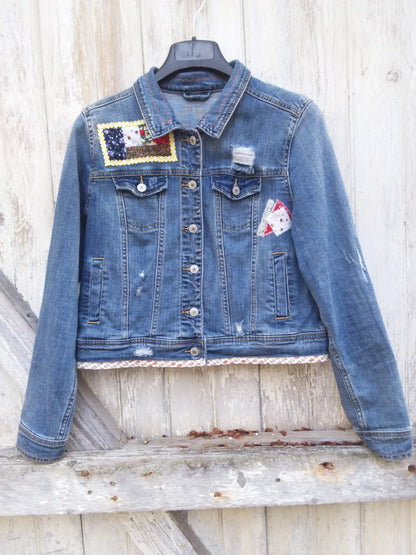A denim jacket with patches hanging on a wooden wall.