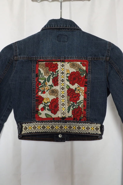 An upcycled cropped denim jacket with roses and lace on it