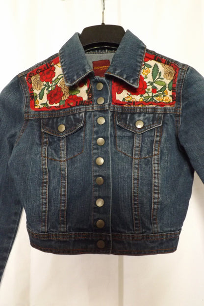 An upcycled denim jacket with roses and leaves on it.