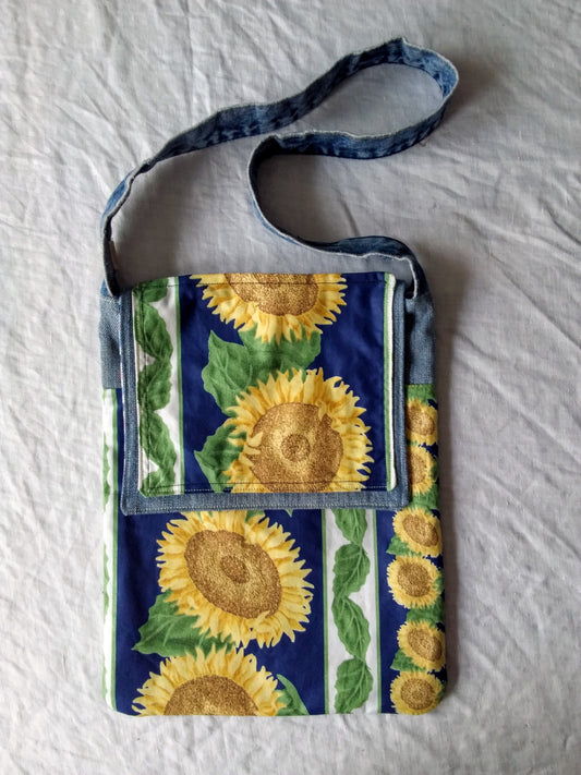 An upcycled denim messenger bag with sunflowers on it.