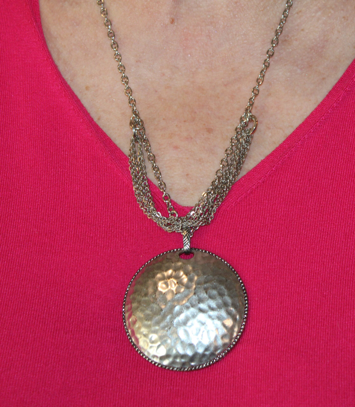 A woman wearing a pink top and a silver necklace.
