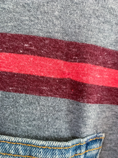 A close up of a grey t - shirt with a red stripe.