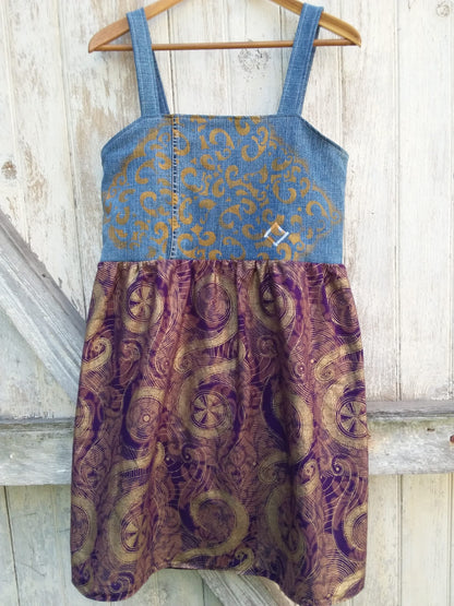 a gold and purple dress hanging on a wooden hanger.