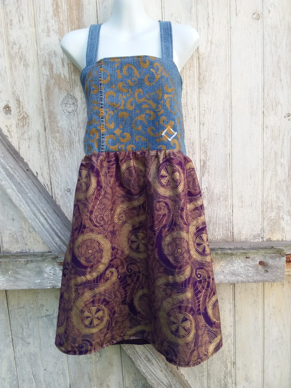 A mannequin with a hand painted, upcycled denim dress on it.
