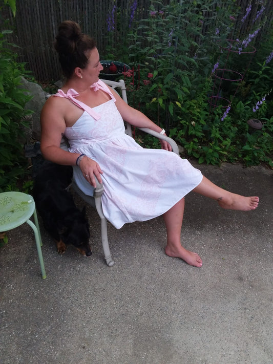 A model wearing a pink and white floral, summer dress created with repurposed textiles