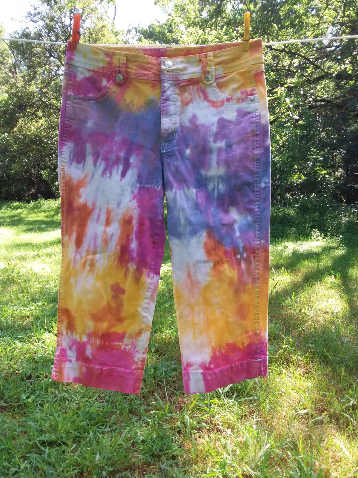 Upcycled tie dyed jeans in shades of pink, yellow, orange, purple and blue.