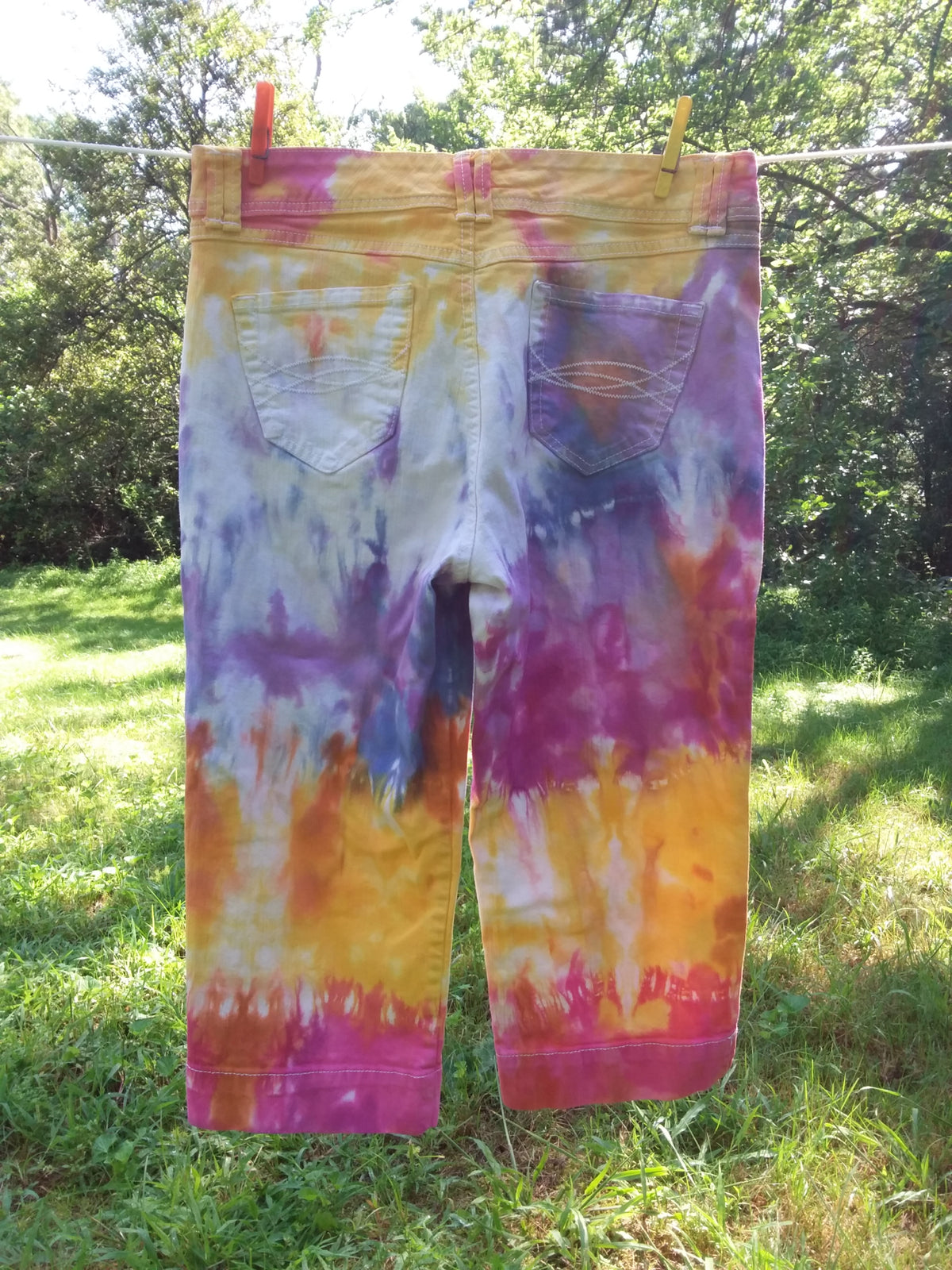 Upcycled tie dyed jeans in shades of pink, yellow, orange, purple and blue.