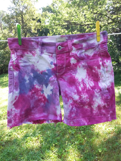 A pair of pink and purple tie dye shorts hanging on a clothes line.