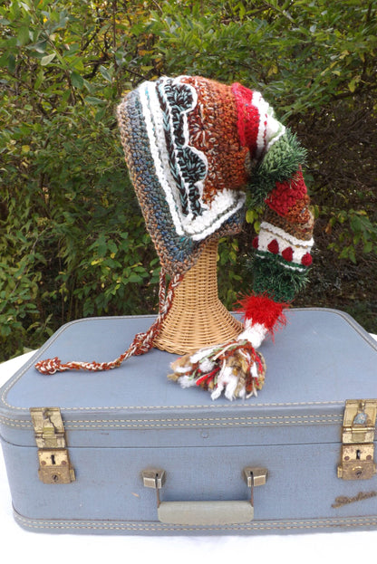 A crocheted hat sits on top of a suitcase.