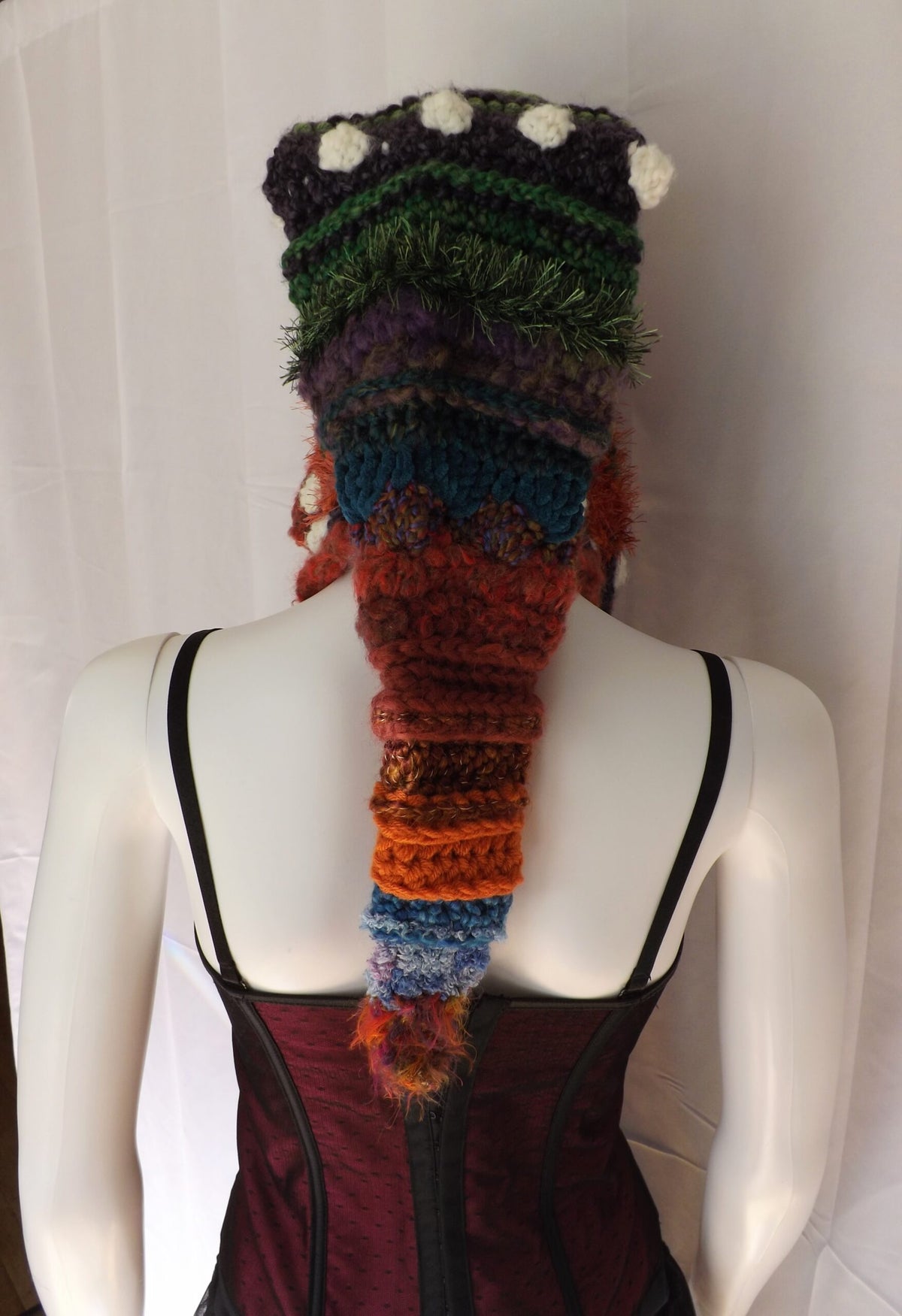A mannequin wearing a colorful crocheted hat.