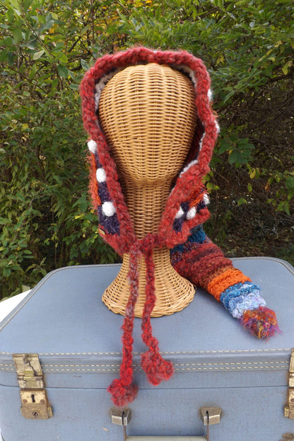 A crocheted hooded hat on top of a suitcase.