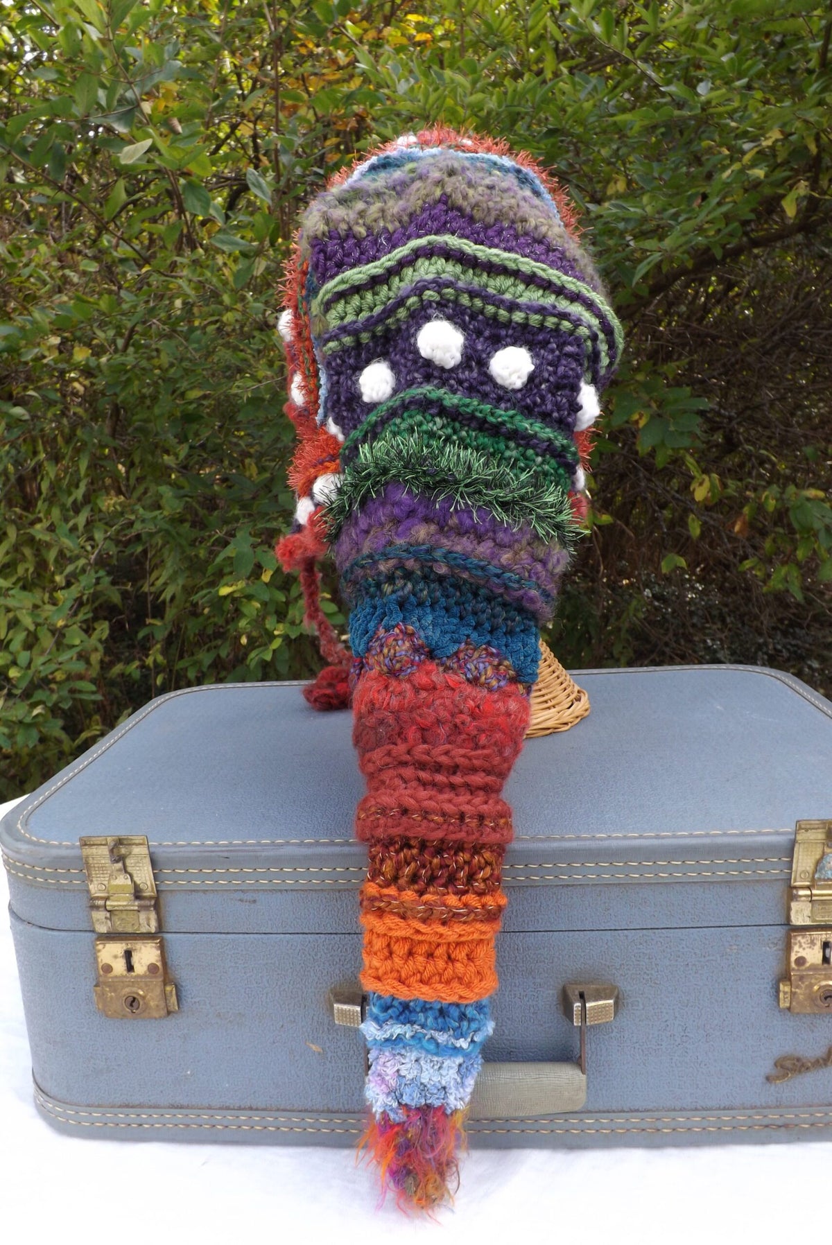 A crocheted hat on top of a suitcase.