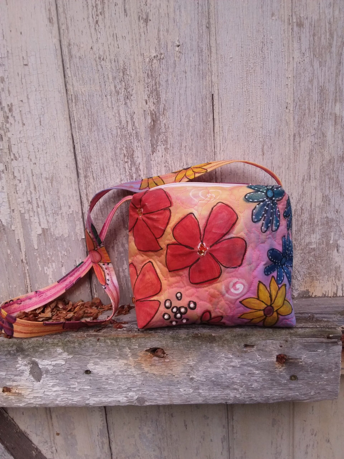 Colorful painted flowers adorn an upcycled bag with beaded accents