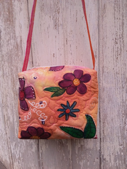 A unique upcycled bag with bold red, purple and blue flowers on an orange and pink fabric
